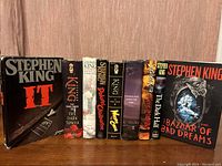 Nine hardcover Stephen King books arranged standing side by side, showing front covers with dust jackets.