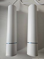 Two identical white aluminum cylindrical pendant lights with a blue line near the bottom edge, shown side by side on a white surface.