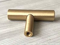 Single brass T-shaped drawer pull handle showing threaded hole for mounting screws, brushed brass finish, approximately 1 inch long.