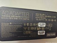 Close-up of AC adapter label showing model A17-150P1A, input 100-240V 50-60Hz 2.0A, output 19.5V 7.7A, safety markings, and brand HUIYUAN.