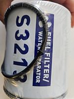 Close-up front view of the cylindrical white metal fuel filter showing part of model number S3213 and the attached black O-ring.