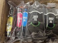 Five sealed HP 902XL ink cartridges in various colors: two black, magenta, cyan, and yellow.