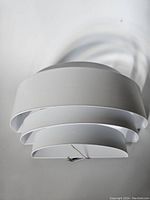 Top view of the white metal wall sconce showing the three-layer semicircular design and wiring.