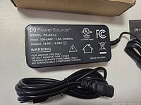 Top flat view of PowerSource black rectangular laptop charger label showing model PS-AS3-2 and power output specifications and warnings.