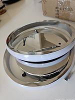 Two round modern LED ceiling light fixtures with chrome rings and white diffuser panels, showing close-up views of the metallic frame and wiring.