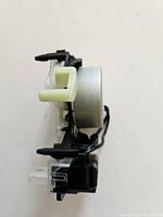 Side view of the Whirlpool top load washer shift actuator showing the structural components including plastic and metal parts.