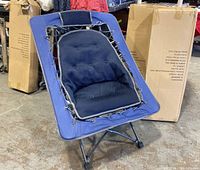 Front view of a single foldable chair showing blue fabric with black tufted cushion and metal tubular frame with rubber feet.