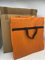 The folded orange carrying case of the jade heat mat with a cardboard box in the background.