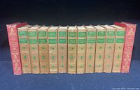 Front view of two red hardcover volumes of The Works of Voltaire flanking eleven green and beige hardcover volumes of World's Greatest Literature.