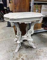 Full view of the shabby chic table showing the carved white wooden base and the marble top in place.