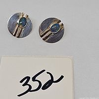 Pair of round sterling silver geometric pierced earrings with oval opal stones on a white background.