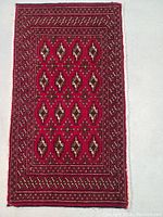 Full view of the rectangular Turkman wool rug with red background and geometric patterns.