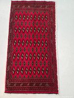 Full view of the red Persian Turkmen rug showing diamond pattern and border detail.