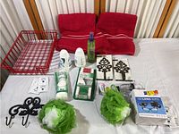 Lot items arranged on surface showing full set of bathroom collection including basket, towels, hooks, poufs, deodorant, wipes, and other toiletries.