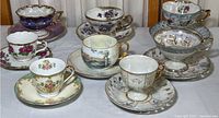 Seven colorful and ornate porcelain teacups with matching saucers, showing variety in size, color, and decoration