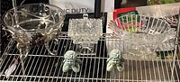 Full collection on metal rack including large glass bowl with metal stand, square crystal candy dish, glass fruit bowl, and two green composite angel figurines.