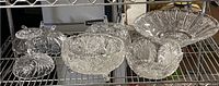 Front view of the collection showing five crystal and glass bowls of varying sizes with intricate cut patterns, arranged on a metal rack