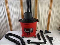 Full view of red Sears Craftsman 16 gallon wet dry vac with hose and attachments laid out on white surface.