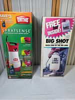 Photo showing the front of the two boxed sprayers side by side, Ortho SpraySense on left, Big Shot by Roundup on right.