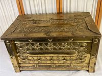 Top view showing embossed ornate brass lid with geometric and floral patterns and riveted construction.