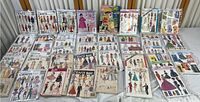 Wide view of all doll dress patterns laid out showing 30 vintage patterns.