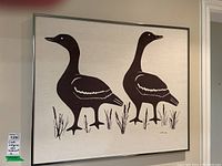 Front view of framed screen print showing two Canada geese on cream cloth set in silver metal frame.