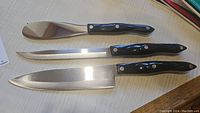 Three Cutco knives arranged horizontally on tabletop