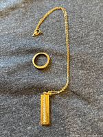 Overview of bar pendant on chain alongside hinged ring