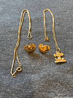 Full lot showing two chains and pair of earrings on cloth background