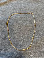 Full view of necklace laid flat on dark fabric.