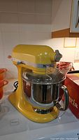 Front-left three-quarter view of yellow mixer on countertop with bowl attached
