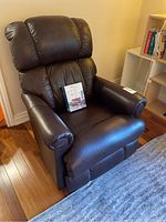 Front angled view of recliner showing leather upholstery and care kit on seat