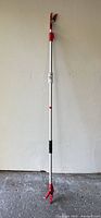 Full length photo of the extendable wand pruner with red and black blades on top and red bottom grips.