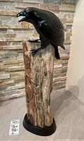 Full view of the 'Story Teller' sculpture showing raven on totem and base