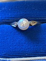 Ring front view in blue velvet box showing pearl and side stone chips