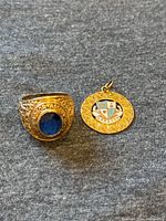 Ring and charm side by side on gray fabric showing overall lot contents