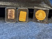 Three items displayed together: JM silver bar, JM gold bar, and Chinese Panda coin