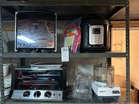 Photo of two shelves containing the toaster oven broiler, Instant Pot, Cuisinart food processor, and accessories