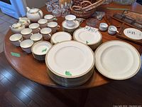 Overview of entire Wedgwood Gold Ulander bone china set arranged on wooden table.