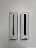 Boxed Microsoft Surface Stylus pen, upright in its original white box with product image and branding visible.
