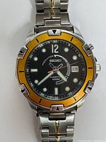 Front view of Seiko watch face with yellow bezel and black dial, showing brand and details.
