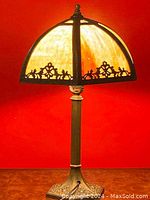 Full view of antique slag glass table lamp showing base, column, and illuminated shade with brass frame