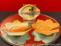 Three antique hand painted dishes, two large leaf-shaped with wheat detail and one small dish with a tree landscape, arranged on a reflective surface