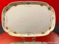 Top view of the rectangular porcelain tray showing overall floral and gold design on cream background against red surface.