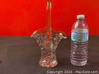 Front view of the Duncan Miller crystal glass basket with etched floral design, shown next to a water bottle for scale.