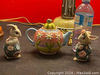 Photo of two Noritake porcelain rabbit figurines and a floral hand-painted teapot on a dark surface.