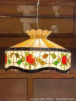 Full view of Tiffany stained glass chandelier with floral rose motif, showing scalloped edge and yellow petal top design suspended by chain.