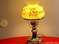 Full view of vintage brass hurricane lamp with milk glass shade showing floral hand-painted design and brass base.