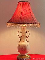 Vintage porcelain hand painted table lamp lit with shade on a wall background