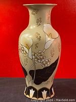 Full front view of vintage porcelain vase with hand painted white calla lilies, clusters of small flowers, black leaves and gold swirls on cream background.